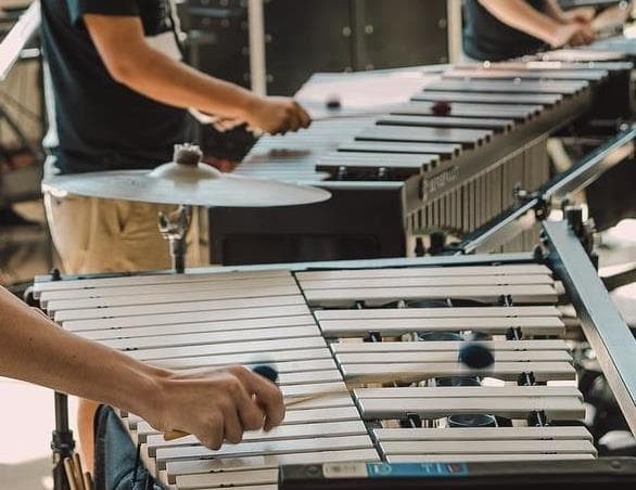 A percussionist holding mallets above a keyboard instrument