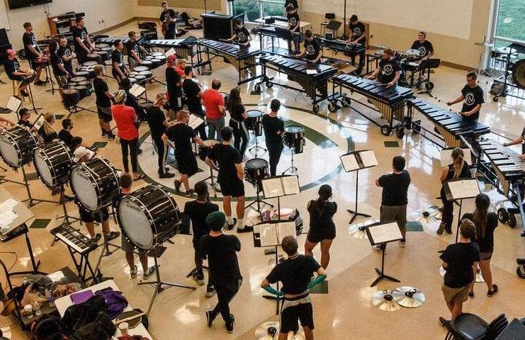 A percussion ensemble arranged in a rehearsal space